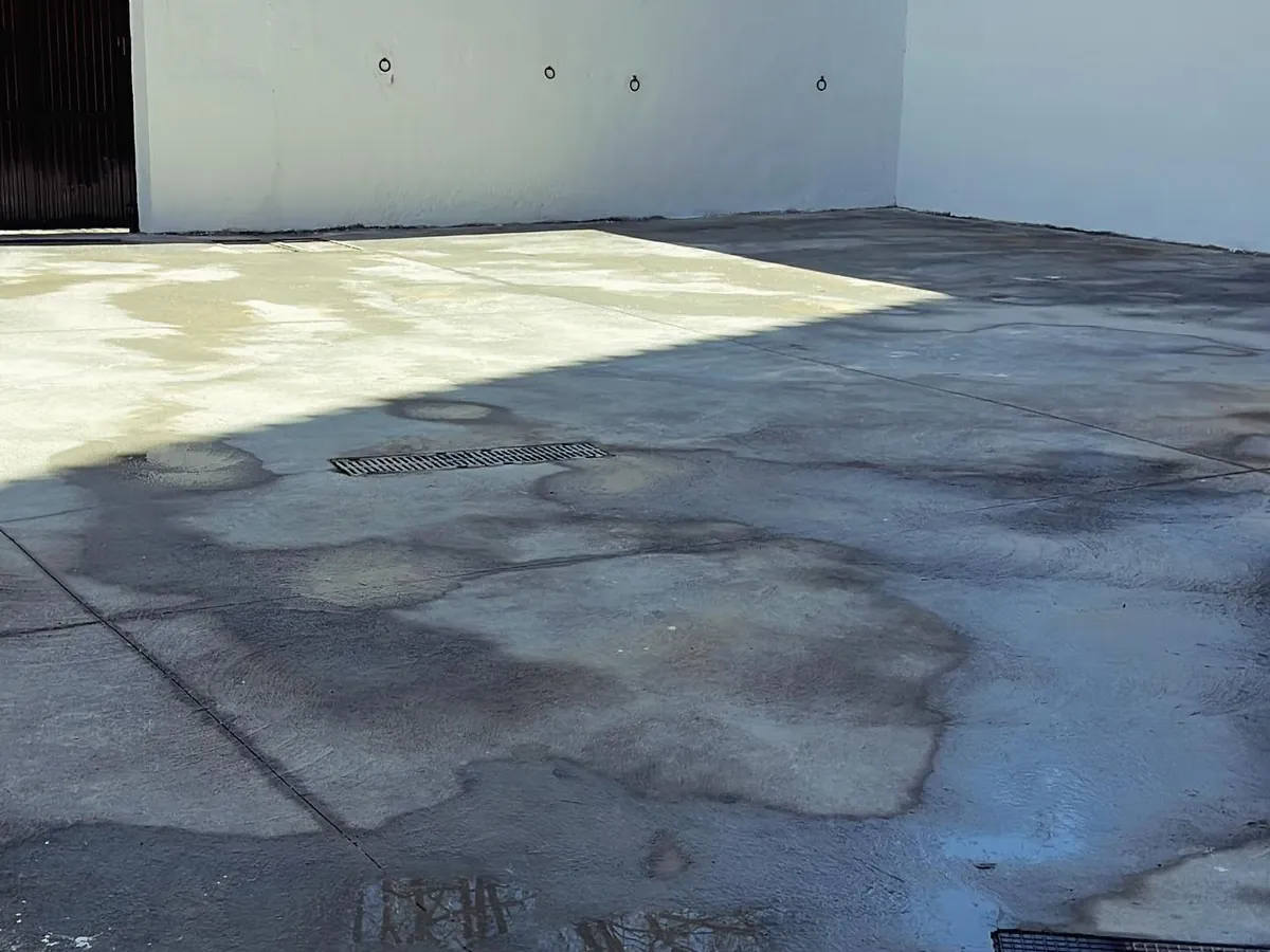 Patio exterior con el suelo de hormigón recién baldeado y las paredes blancas