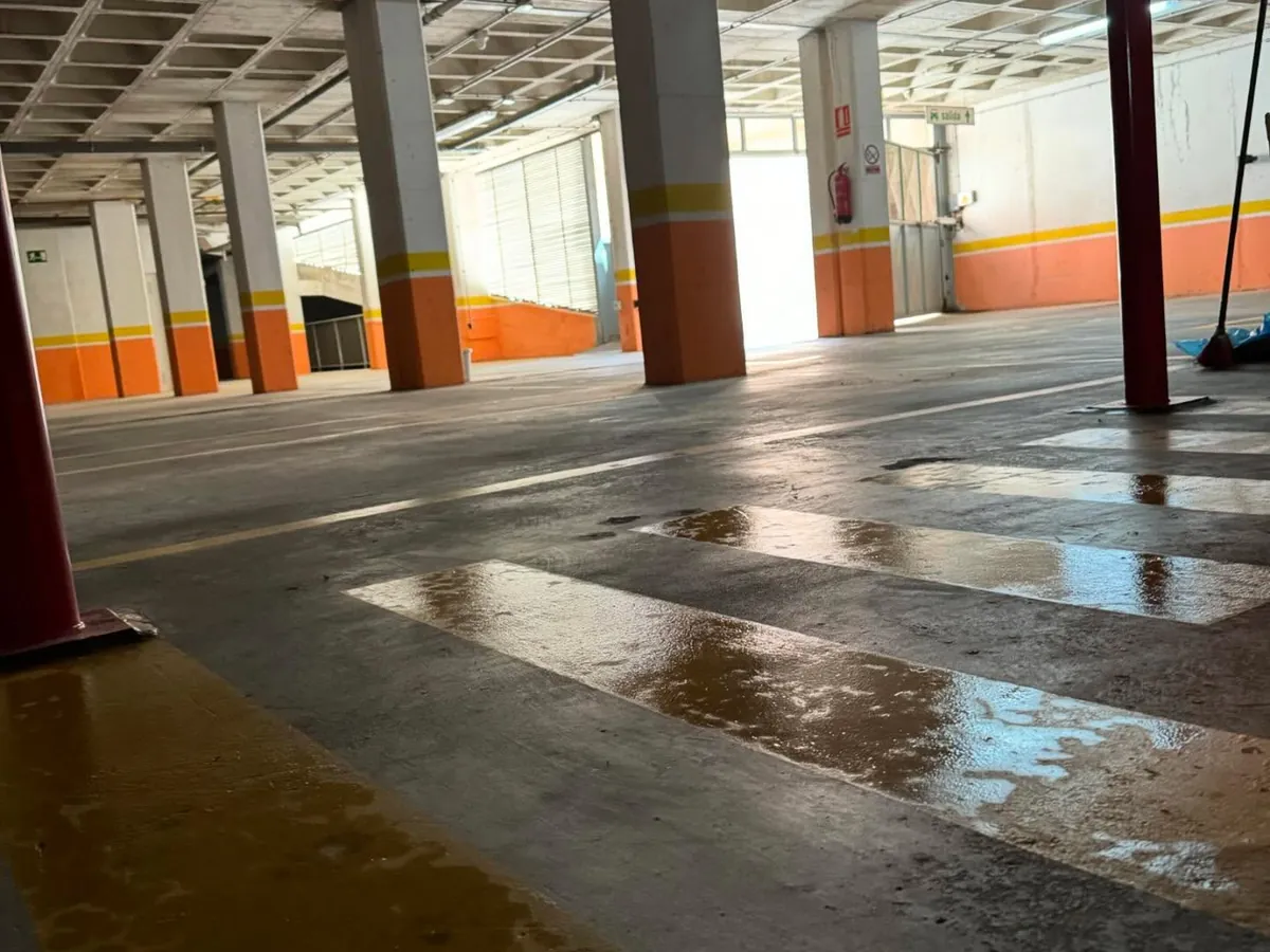 Suelo de un garaje comunitario recién fregado, con las columnas pintadas de naranja